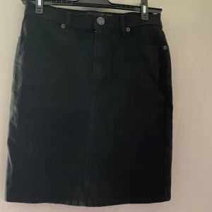 Svart jeanskjol,  snålt använd - Superfin svart jeanskjol i strl 38 som sitter superfint!  I nyskick då den inte alls är mycket använd. 