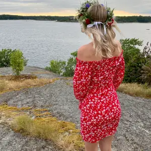 Röd off shoulder klänning m. vita små blommor. Dekorativt ”V” i urringningen. Nyskick, storlek XS, från Nelly.