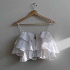 Volang topp  - Vit sommrig topp från Ginatricot i storlek 36 🤍 jätte fint linne med volanger i fint skick! 🌟 Dragkedja på ena sidan som ej syns utifrån, bara att skriva och fråga vid frågor eller för fler bilder 🤍 Köparen står för frakten! 🌟