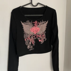 svart tröja med coolt tryck  - en svart långärmad tröja med ett coolt tryck. trycker är rosa och hor rhinestones. kontakta vid flera bilder eller frågor!! <33