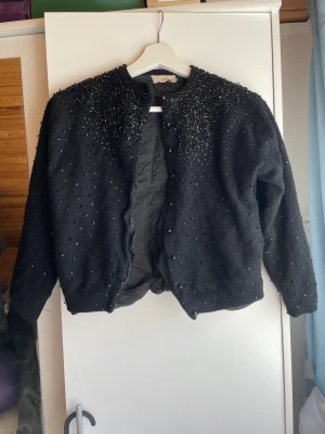 Kofta i ull och angora - Svart, mjuk pärlbroderad kofta av ull och angora. Foder i silkesliknande material. Fortet har lossnat längst ut på ena ärmen, men lätt att sy fast igen