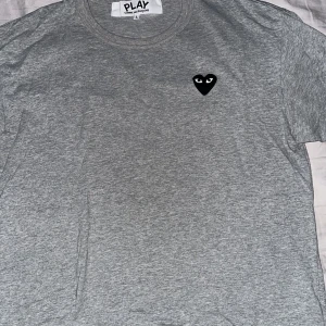 CDG T-Shirt - Säljer min gråa och svarta CDG tshirt. Säljer en liknande i storlek Medium. Denna passar mig som är 190 väldigt bra. Skick är 9/10. Finns inget kvitto. DM för mer bilder.