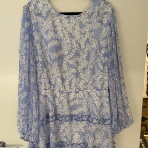 Blommig blå klänning i chiffong med öppen rygg - Superfin blommig klänning med öppen rygg ifrån Gina. Använd en gång. Säljer på grund av att den inte kommer till användning🩵🩵 Storlek 46