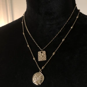 Guld halsband - Guld halsband med dubbla kedjor. Hängena har två olika tryck. Längd ca 49cm. Vikt ca 12g.