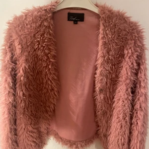 Rosa bolero från Zoul - Rosa kofta  / bolero från Zoul säljes.  Knäpps via tre tryckknappar.  Storlek XS.   Finns i ett djur- och rökfritt hem på Kungsholmen, Stockholm.   