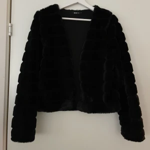 Fuskpäls strl S - Snygg fuskpäls tröja/jacka i nyskick. Använd 1-2 gånger. Går att ha som tröja inomhus på vintern eller jacka vid mildare väder. Kan stängas med en hyska & hake mitt på bröstet. Storlek S. 100% polyester 