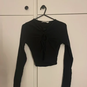 Svart blus - En långärmad blus från nakd med hål mellan brösten. Den är ursprungligen från NA-KD i bra skick. Den passar bra till finare tillfällen!