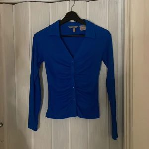 Topp - Blå topp från H&M, liten krage och med knappar använd en gång. 
