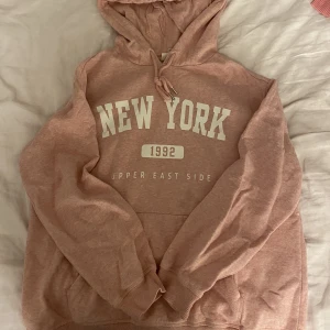 Rosa hoodie - Rosa hoodie i fint skick. Ficka på magen samt tryck. Luva. Liten fläck på magen (se bild)