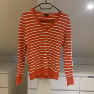 En orange och vit  randig stickad långärmad tröja