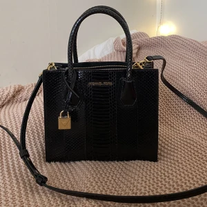 Michael Kors ormskinsväska  - Michael Kors i vattenormssskin Modellen Mercer crossbody väska  Höjd 19cm Längd 21,5cm Bredd 10,5cm  Inte använd så mkt, har förslitningar på handtaget i fram, syns på bilden.  Inköpt för 8000kr, dustbag finns.