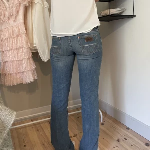 lågmidjade Wrangler jeans - Midjemåttet är 40cm tvärs över och innerbenslängden är 86cm. Modellen är 172 och bär normalt sätt storlek 36. Jeansen har täcken på användning men varit väl omhändertagna🤍