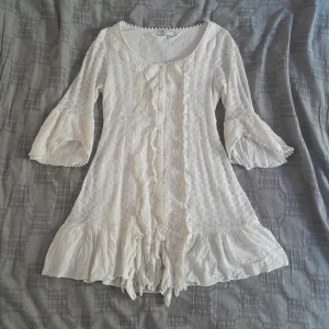 Vit kort klänning - Hela klänningen är 76 cm lång, ärmarna är 46 cm. Varan är i ett bra skick. Den såldes originellt som en tröja men jag har använt den som en klänning vilket har funkat bra för mig!