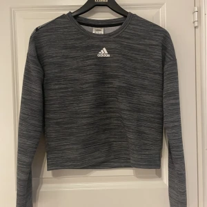 En Adidas Sweatshirt  - En väldigt fin Sweatshirt med färgen mörkgrå med vita små ränder på. Har används sällan och är i bra skick.