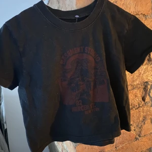 Svart t-shirt - Svart t-shirt med snyggt tryck, lite kortare, passar xs/s. Från Brandy Melville 