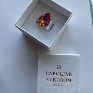 Helt oanvänd, en jättefin silverring med en unik färg som jag inte kan hitta på Caroline Svedboms hemsida, rosa orange. Det är en One Size då den är reglerbar på baksidan. Jättefin till sommaren! Säljer den då jag ångrade köpet, köptes på utförsäljning!