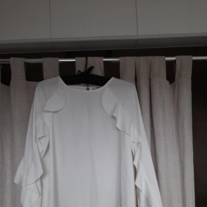 Vit blus - Vit luftig blus från gina tricot. Blusen har fina volanger längs med sidan på ärmarna, både på framsidan och baksidan.