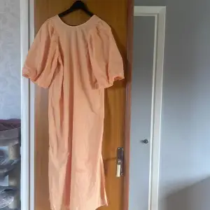 En orange klänning med puffärm, älskar den men beställde i fel storlek, endast provat den en gång