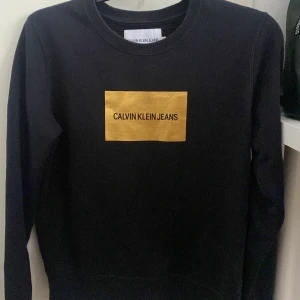 Calvin Klein sweatshirt svart/guld  - Normalanvänd tröja i fint skick. Strl. S