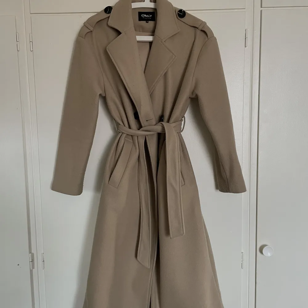 Kappa från Only, snygg beige färg till hösten och passar alla outfits. Ny pris 900-1000kr Storleken är xs men passar mig som oftast bär S/M och är 166cm. Andra bilden är hur kappan ser ut utan band i midjan. . Jackor.