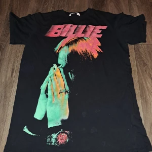Billie Eilish t-shirt - En Billie Eilish T-shirt, Köpt ifrån H&M. Knappt använd. Den har några Fläckar och vet inte en om det går bort i tvätt, Den Tvättas Självklart innan den skickas. Jag skulle säga att den är liten i storleken 