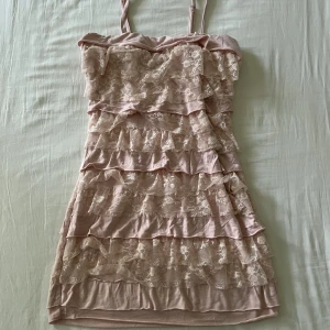 Guess rosa spets tub klänning - As snygg rosa tub klänning med volangdetaljer i spets, från Guess. Axelbanden är både justerbara och avtagbara. Klänning kan användas både som en topp eller som en mini klänning. Begagnat fint skick, inga fläckar eller hål! Storlek XS men passar även S🫶💕