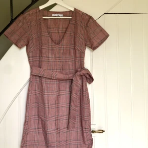 Rutig klänning - Mini klänning i rutigt mönster från NA-KD med söt liten knytdetalj! Originalpris 399kr.