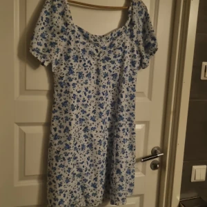 Sommarklänning  - En vit klänning med blå blommor.jättefin klänning och som är perfekt till sommaren. Säljer den då den tyvärr inte passar mig längre. Den är använd ett få antal gånger bara. Den är i storlek L. Priset kan diskuteras 