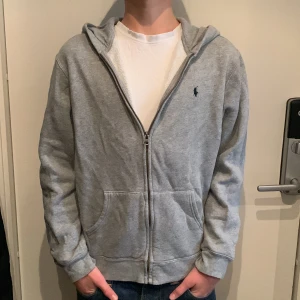 Ralph Lauren zip hoodie - Ralph Lauren zip hoodie i använt skick utan några större defekter. Säljer då jag inte gillar hur den sitter runt midjan. Modellen på bilden är nästan 170cm.