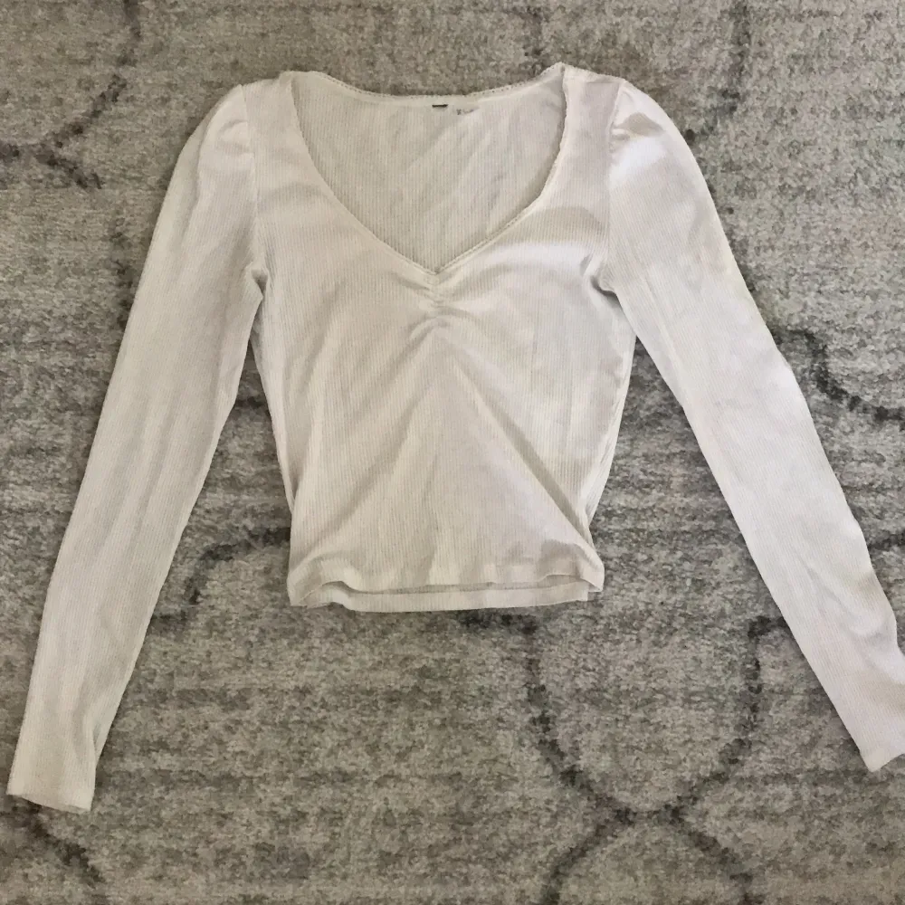 Säljer denna vita långärmade tröjan med ribbat tyg och detaljer längs kragen <3 (den är inte cropped) Tryck på köp nu!. Toppar.