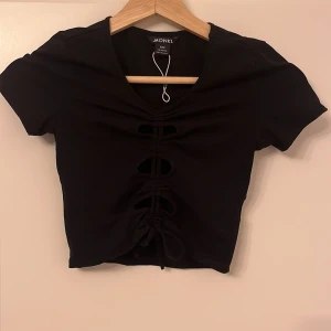 Cool svart tröja - Cool svart topp med hålrum och snörning från Monki i storlek xxs! Den kan passa för en xs också då den går att reglera med hjälp av snörningen! Jättecool och fin topp💕💕