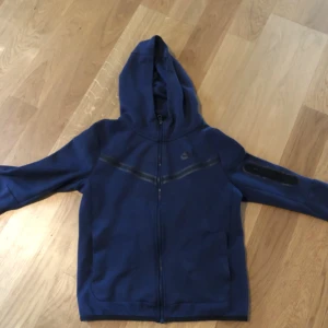 Nike teck fleece BLÅ - Det är en Nike tech flecce som är för liten för mig. Den är i storlek L junior. Den är lite syd vi fickan men syns knappast.