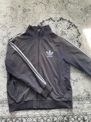Adidas tunn zip up grå  - en grå tunn adidas zip up perfekt till sommaren. loggan är ljusblå. storlek XL men passar mer som M eller L. Den ända defekten är att ”Adidas” loggan på blixtlåset gick sönder men det går att knäppa hoodien utan problem. skriv privat för mer info💕