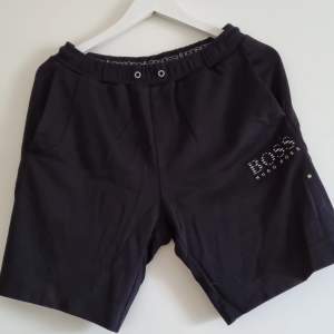 Svarta shorts med silvriga/grå detaljer, reflekterande. Fint skick men snöre saknas.