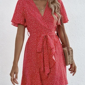 Mönstrad röd klänning  - Elegant röd mönstrad klänning som sitter bekvämt och snyggt, har ett snöre runt midjan och volanger ner till använd 1 gång i storlek S