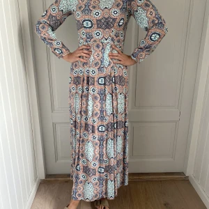Vintageklänning från H&M - Så fin och speciell vintageklänning från H&M. Härliga färger och vackert fall. Storleken säger 36 men är som en 38:a. Maxiklänning. Modellen är 173 cm.