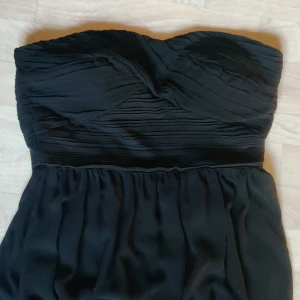 Klänning  - Svart festklänning med en sneskuren fåll. Faller väldigt snyggt. 