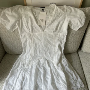 Zara klänning vit broderad  - Broderad vit klänning från zara, slutsåld. Lapparna kvar.  Tightare i midjan med volang kjol. Storlek M 