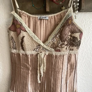 Topp unik - Tar emot o sälja denna fina topp men den passar tyvärr inte mig! Smutsrosa färg och benvita spetsdeltaljer och axelband. En liten defekt men sömmen vid ena axelbandet men det går att fixa! Broderat motiv vid bysten. 