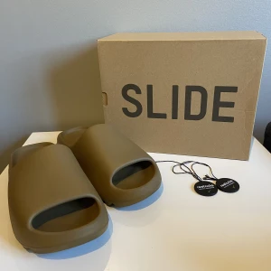 Yeezy slide - Säljer ett par Yeezy slide ochre i storlek 44 1/2. Jag säljer pga att de är för små för mig och därför köpt nya. Inte använda mycket så dem är i ett bra skick, endast ett märke på vänster fram. Köpte dem på restocks, mer info och bilder privat.