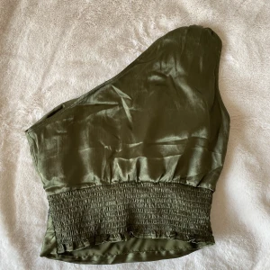 One shoulder topp - Säljer denna mörkgröna one shoulder topp i storlek 34. Aldrig använd. 
