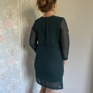 Samsoe mörkgrön klänning strl M - Helt ny med lappen på! Transparent trekvarts arm. Dragkedja där bak. Har lite mer självfall om dina höfter är åt det smalare hållet. 