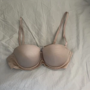 Beige BH med avtagbara band - Bh:n är endast använd ett fåtal gånger. Axelbanden går att ta av så den är perfekt till off shoulder tröjor eller klänningar. 