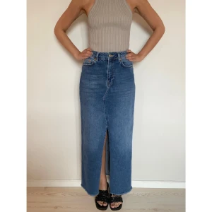 Denim kjol - Denim kjol omsydd av ett par jeans. Jeanstyget är stretchigt och har råkant längst ner. Storlek M Mått: Midja: 78cm Längd: 99cm