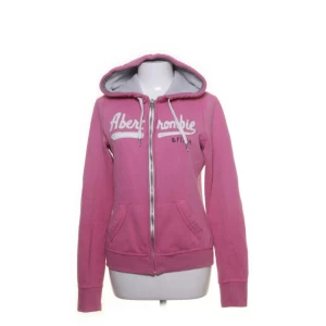 Abercrombie & Fitch Hoodie - Säljer denna supergulliga rosa hoodien från A&F. Varan är i storlek L, men är tyvärr lite för kort i ärmarna för mig som ör ca 176 cm lång. Hoodien har dock några få diskreta tecken av användning vid blixtlåset🫶🏼