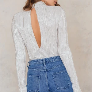 Silvrig/grå plisserad topp - Slutsåld silvrig/grå plisserad topp med turtleneck, öppen rygg och långa ärmar från NAKD i storlek XS men passar även mig som är en S. Använd 1-2 så fint skick! 🩶🥰