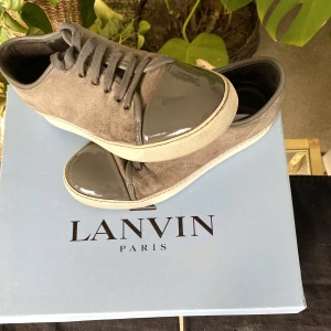 Lanvin Patent Cap Toe Sneaker Beige - Hej, säljer ett par Lanvin Patent Cap Toe Sneakers i bra skick. Perfekt Toebag utan några repor eller fläckar. Beige/brun och somrig färg, perfekt inför varmare väder. Har dustbags ifrån köp. Nypris runt 4000 kr. Size 5 vilket motsvarar 40/40,5. Hörs!