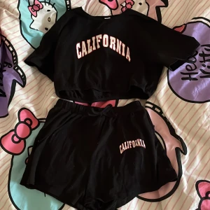 Svart California set tröja och shorts  - Säljer för att de aldrig har använts. Fint skick och helt fläckfri.  Tröjan ett gummiband runt magen. Shortsen har ett spänne runt midjan. Klicka på köp du vill ha. Kontakta om du har frågor. 