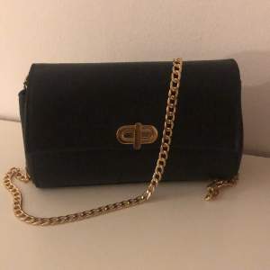 En liten svart handväska med guldigt kedjeband. Aldrig använd