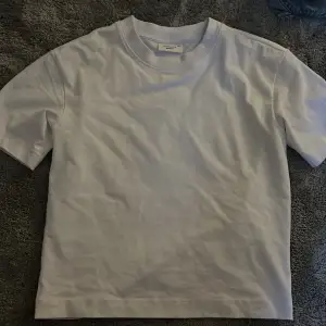 En jättefin vit t-shirt från gina😊deras lite kortare modell som slutar  typ under naveln😊använd fåtal gånger🫶🏻